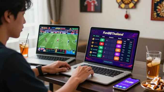 Engaged Thai bettor using Fun88Thailand on laptop and smartphone amidst lively atmosphere.